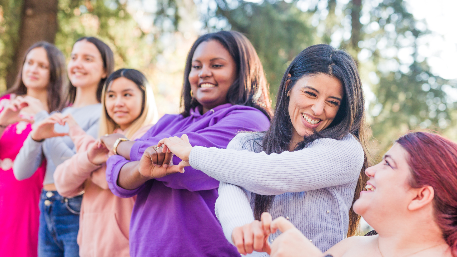 Diverse college students forming heart shapes outdoors, symbolizing community through Cougs 4 Kids mentoring at WSU.”