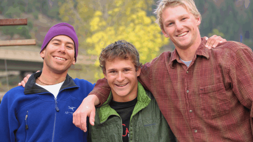 Three college‑age volunteers smiling outdoors, representing WSU Greek Life mentors serving with Cougs 4 Kids.