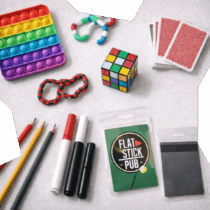 Flat-lay of enrichment items for teens including fidget toys, a puzzle cube, playing cards, art supplies, and a Flat Stick Pub gift card, arranged on a light background to suggest play, connection, and stress relief.